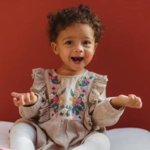 Musikgarten für Babys in Fürth - ein lachendes Mädchen mit dunkler Haut und süßen Locken